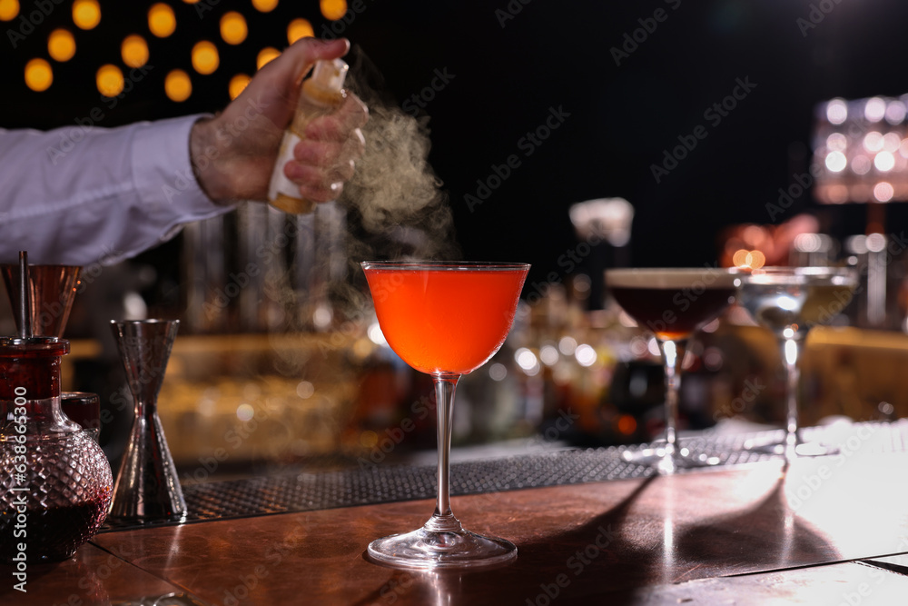 Poster Bartender preparing fresh Martini cocktail in glass at bar counter, closeup