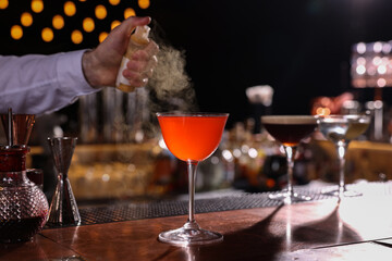 Bartender preparing fresh Martini cocktail in glass at bar counter, closeup