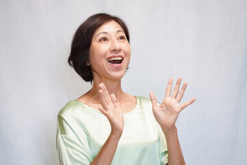 上を向いて両手を開いて驚く中年女性　拍手する中年女性
