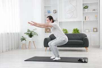 Senior man in sportswear doing exercises on mat at home