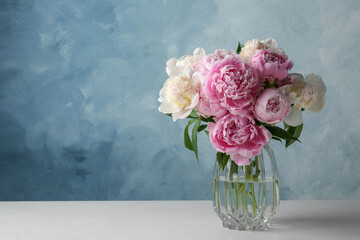 Beautiful peonies in glass vase on white table. Space for text © New Africa