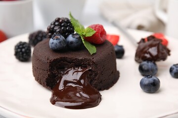 Delicious chocolate fondant, berries and mint on plate, closeup