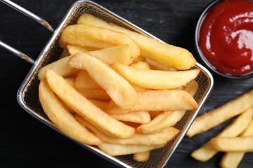 Tasty french fries and ketchup on dark wooden table, flat lay