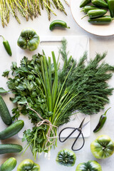 Bunches of herbs bound by twine and surrounded by green vegetables.