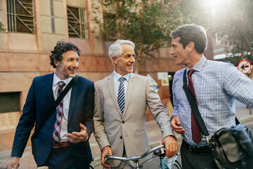 Diverse group of businessmen commuting together to work with bicycles and talking on the way there