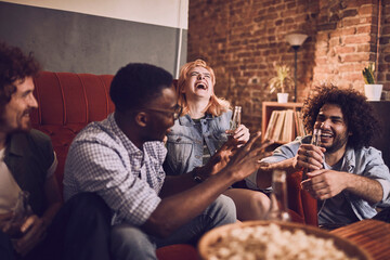 Diverse group of young friends having a pizza party at home on the couch