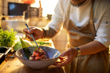 Male asian chef preparing a traditional food dish in a restaurant kitchen