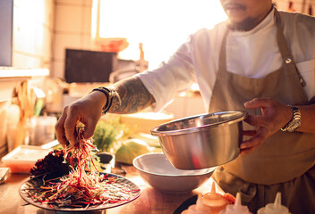 Male asian chef preparing a traditional food dish in a restaurant kitchen