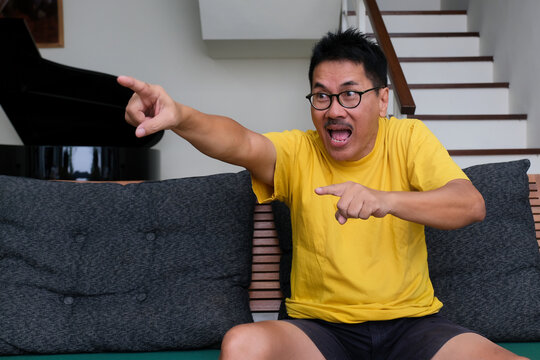 Man Sitting Alone Excitedly Pointing His Finger Forward Seeing Football On TV