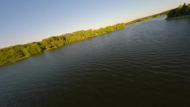 Drone flight approaching the shoreline of lake Baluosas in Lithuania during sunset