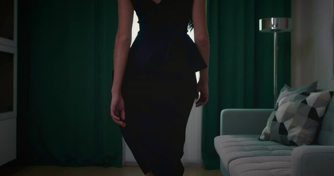 sensual young woman in black dress walking to window of apartment, back view, 4K, Prores