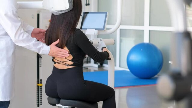 A professional vertebrologist and a patient on a back exercise machine. 