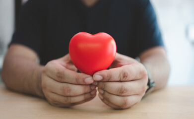 Male hands cradling a red heart with love. Health insurance or love concept