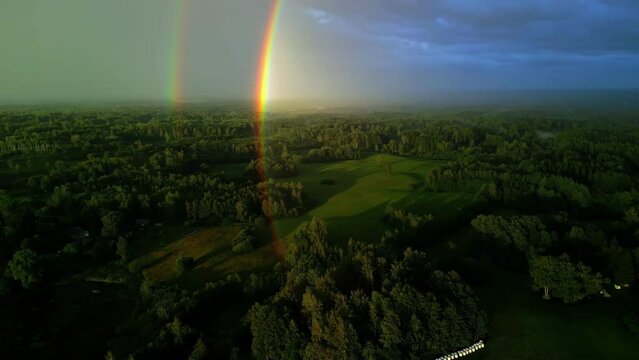 Double rainbow over woodland landscape, aerial drone view