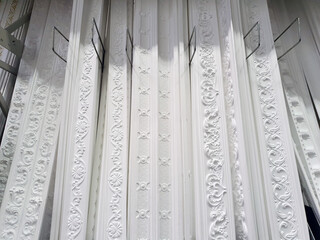 ceiling cornices, different types of white foam plastic ceiling moldings at store showcase, demonstration stand samples, showroom © Анастасия Бурлакова