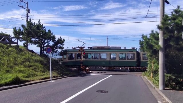 夏の鎌倉、海が見える踏切として有名な七里ガ浜にある江ノ電の踏切。踏切を通過するレトロな電車。
