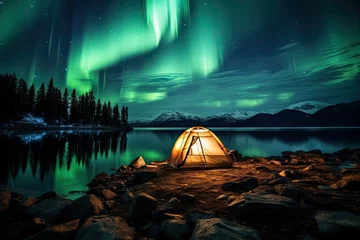 Foto auf Acrylglas Nordlichter A tent glows under a night sky full of stars and aurora