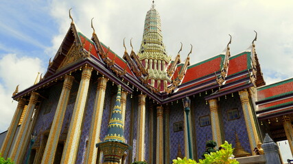 Herrlicher Tempel Wat Phra Kaeo mit glitzernden Säulen und rotem Dach unter blauem Himmel