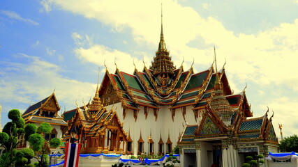 Herrlicher Tempel Wat Phra Kaeo mit vergoldeten Stupas und rotem Dach unter blauem Himmel