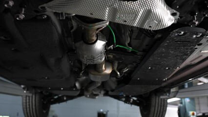 A woman auto mechanic stands at the open hood of a car with her arms crossed over her chest. 