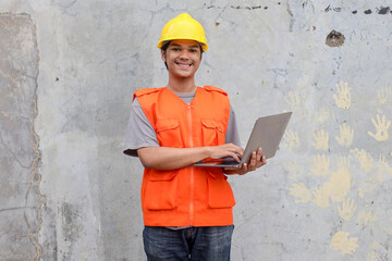 Smiling Asian construction male working on laptop outdoor