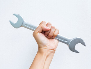 Hand holding double open end wrench on white cement wall background, quality tool industry