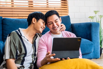 Asian attractive gay couple use tablet shopping online in living room. 