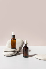 Natural organic product in two glass bottles with a dropper on a background of gray sea stones....