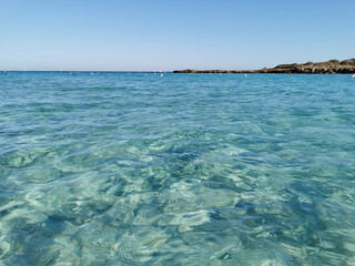 Fig Tree Bay beach, crystal clear water, white sand at the bottom, small island off the coast.