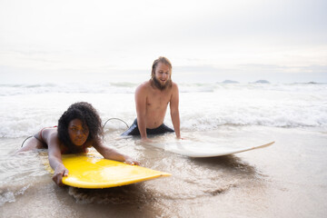 Young man and woman having fun with surfboard in the ocean on a sunny day