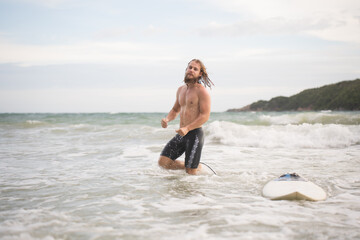 Portrait of a handsome young man with surfboard at the beach