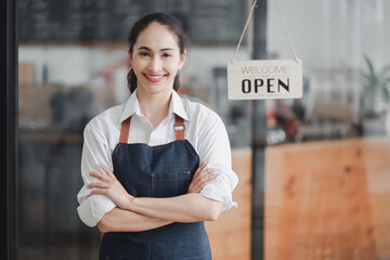 Portrait of happy woman standing at doorway of her store. Cheerful female waitress waiting for clients at coffee shop. Successful small business owner in casual wearing apron standing at entrance.