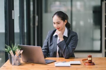 A businesswoman and lawyers are discussing contract papers with a brass scale on a desk in an office. The concepts of law, legal services, advice, justice, and real estate are being discussed.