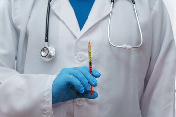 unrecognizable doctor in blue gloves, white coat and stethoscope with a syringe in his hand