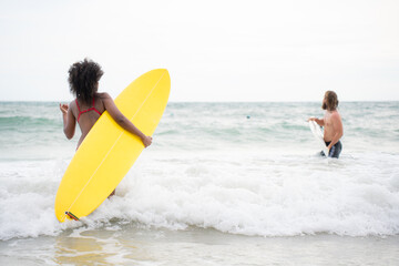 Young man and woman having fun with surfboard in the ocean on a sunny day