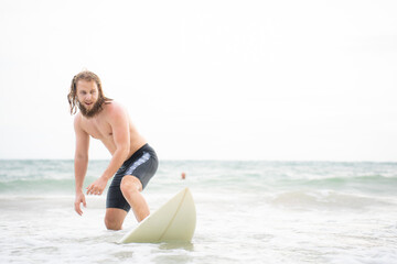 Young man surfing on the beach having fun and balancing on the surfboard