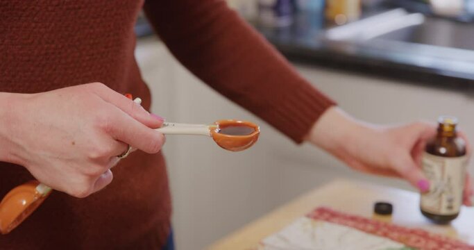Measuring vanilla extract and pouring into mixing bowl with pumpkin spoon