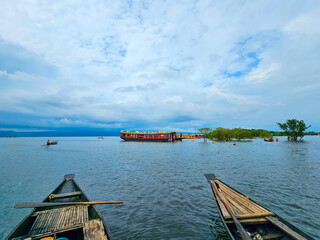 Traditional baots with a houseboat at the Tanguar Haor in Sunamganj, a famous tourist spot in Bangladesh while it was raining during the monsoon season. Rivers of Bangladesh