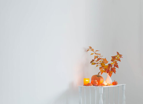 autumn bouquet in white vase on wooden shelf  in white interior