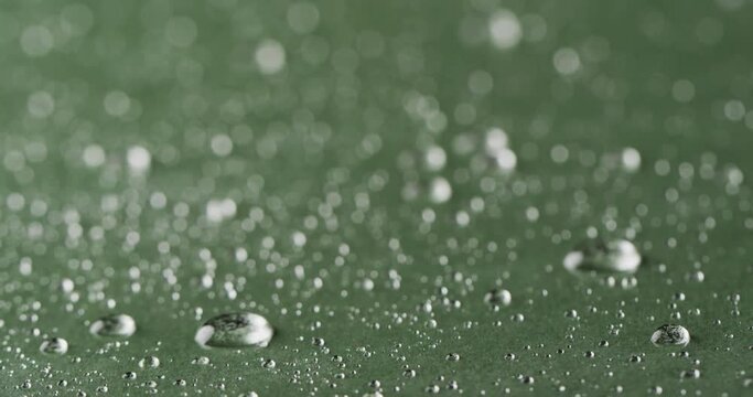 Micro video of close up of water drops with copy space on green background