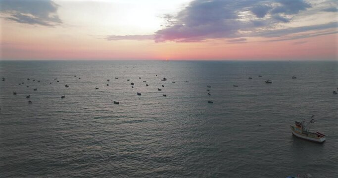Aerial view of beautiful sunset behind in the ocean fishing boats.