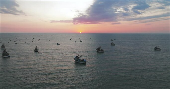 Aerial view of beautiful sunset behind in the ocean fishing boats.