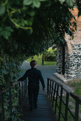 Fototapeta premium A blond man in a black shirt walks down a wooden bridge
