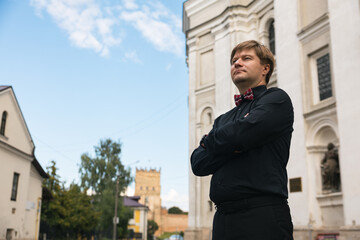 Blond man in a black shirt posing in front of a building
