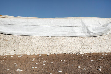 A finished bail of harvested cotton with tarp on top