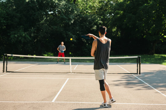 Two young people playing pickleball in the summer