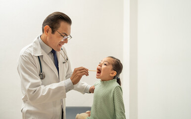 latin doctor checking girl throat using a tongue depressor. Hispanic pediatrician examining kid...