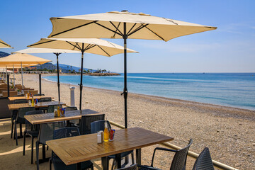 Seaside promenade with outdoor restaurant tables along the Mediterranean Sea in the Old Town of Menton on the French Riviera, South of France