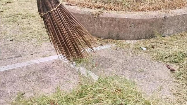 sweep the grass with a coconut palm broom