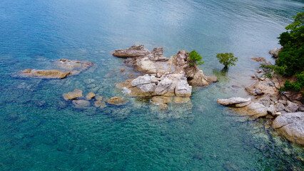 Blue water and rocks. Rocky seashore. Huge stones lie in the shallow sea near the shore.
